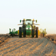 A green John Deere self-driving tractor plows a field.